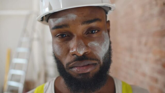 Close up portrait of tired man construction worker with dirty face looking at camera