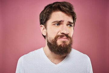 bearded man in white t-shirt emotions displeased facial expression studio pink background