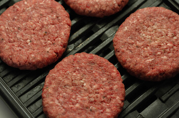 Seasoned beef burgers with a pinch of salt and black pepper on the grill