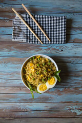 Sliced boiled eggs on a bowl of noodles on a background.