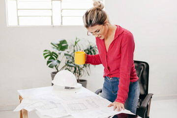 Young architect working in her office. Reviewing architectural design.