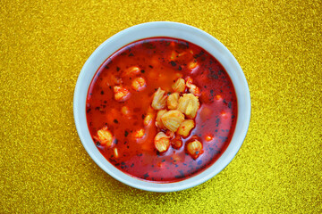 Mexican traditional plate of pozole a broth with corn and red chili.