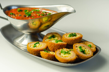 Mini scotch eggs with tomato sauce served on the silver plate