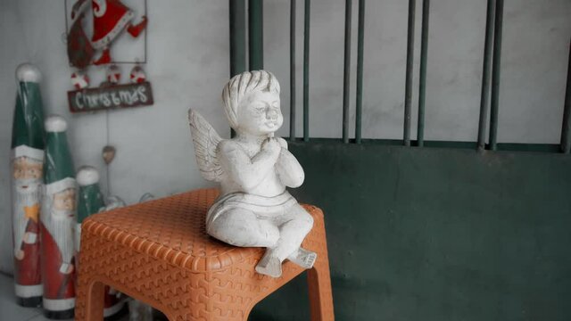 wooden white colourize toy of angel sits on a .chair in the house