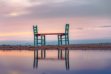 Fototapeta na wymiar Chairs reflection near traditional pictorial coastal fishing village of Milatos, Crete, Greece.