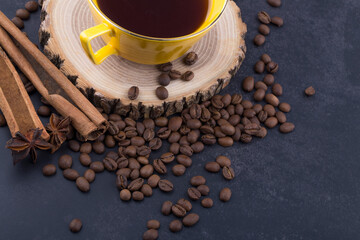 Cup of coffee with coffee beans and cinnamon sticks.