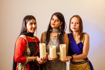 Three women with candles for traditional festival of lights