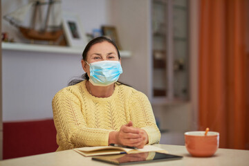 Senior woman in yellow sweater looking in the camera with mask