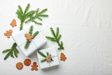 Christmas gifts wrapped in white paper and decorated with spruce sprigs and gingerbread cookies