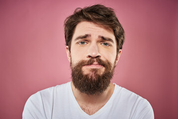 Obraz premium bearded man in white t-shirt emotions displeased facial expression studio pink background