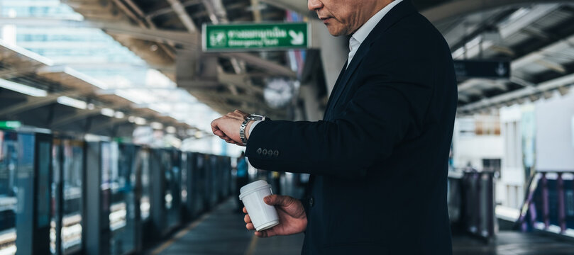 Unrecognizable business man looking at his watch while waiting at train station