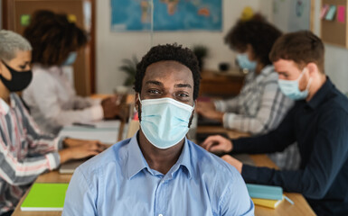 African man wearing face mask in co-working creative space with team work - Young people working during corona virus pandemic