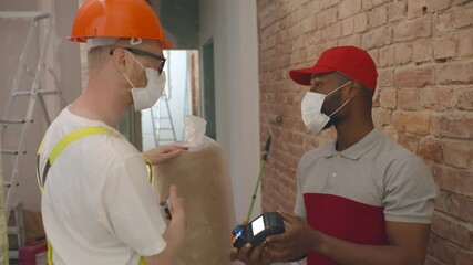 Foreman paying with credit card for delivery to courier at construction site