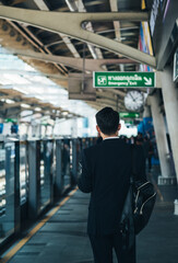 Obraz premium Back view of business man waiting at the train station platform