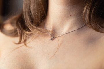 Nude blonde woman's neck with silver necklace close-up.