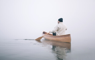 Rear view of man paddling canoe in the winter, copy space