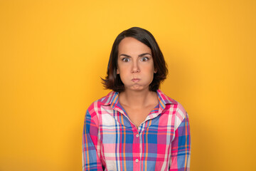 Young pretty girl has gained water in her mouth and is silent on yellow background. keep your silence. High quality photo