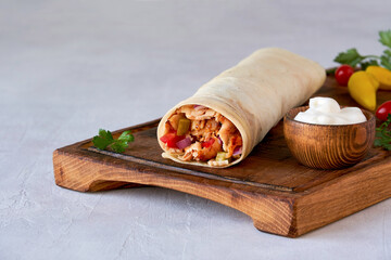 Shawarma with chicken  and garlic sauce on wooden board. Closeup