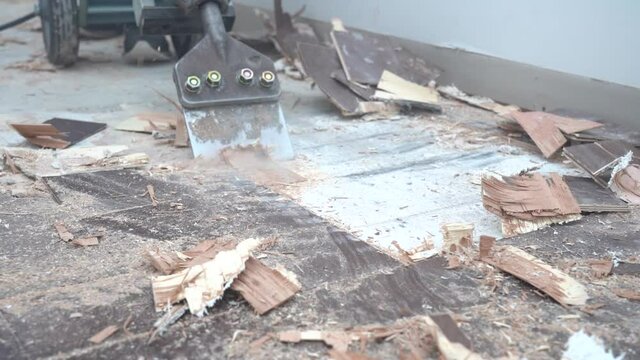 Slow motion footage of a hammer chisel scraping up glued down hardwood flooring from a residential home.