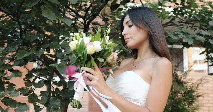 Portrait Of An Idyllic Young Caucasian Girl With A Wedding Bouquet.Beautiful Brunette Bride Looks At Flowers