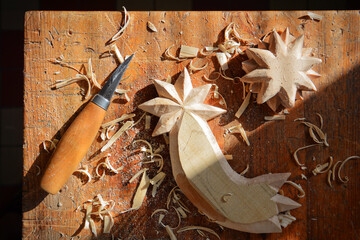 Wood carving from linden wood. Work table in woodworking workshop with carving knife. Woodworking...