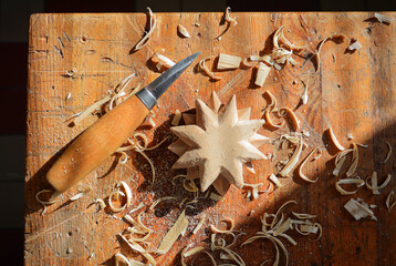 Wood carving from linden wood. Work table in woodworking workshop with carving knife. Woodworking process. 