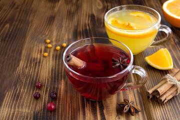 Hot tea with cranberries and sea buckthorn in the glass cups on the wooden background
