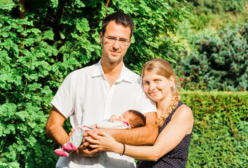 Happy parents with newborn baby outdoors