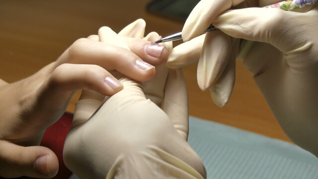 The manicurist applies the bio gel to the client's nails.