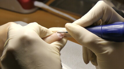 The manicurist cleans the client's nails with a special nail file.