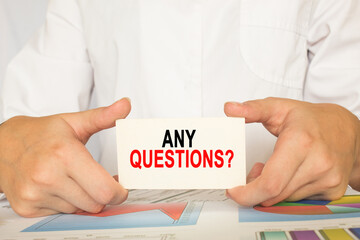 a man in the office holds a card with text ANY QUESTIONS . business concept