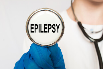 The doctor's blue - gloved hands show the word EPILEPSY - . a gloved hand on a white background....