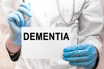 The doctor's blue - gloved hands show the word DEMENTIA- . a gloved hand on a white background. Medical concept. the medicine