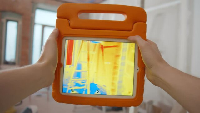 Close up of person detecting heat loss inside house using infrared thermal camera