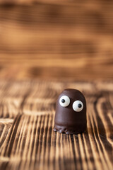 Geist oder Gespenst oder Alien aus Schaumkuss mit Augen aus Zucker auf einem braunen Tisch aus Holz