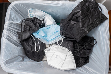 Used disposable Covid 19 face masks in a trash can