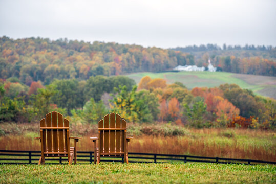 Empty wooden chairs in autumn fall foliage season countryside at Charlottesville winery vineyard in blue ridge mountains of Virginia with cloudy sky day
