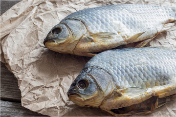 Salted Dry fish vobla on crumpled craft paper on wooden background