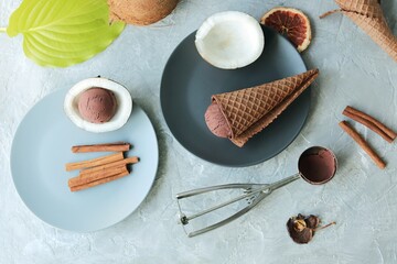Homemade chocolate ice cream in waffle cones, coconuts on a light table, top view, home cooking...