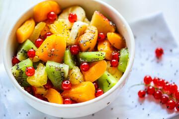 A bowl of fresh berry fruit salad on the white kitchen table. Vegan snack, diet food, healthy food concept. Healthy vegan snack or Breakfast. The concept of weight loss, healthy eating.