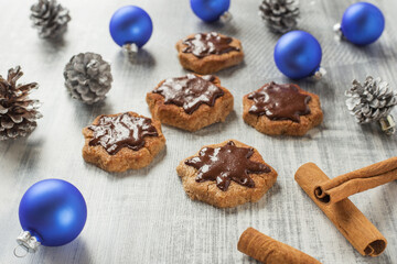 Christmas composition with freshly baked cinnamon cookies, blue Christmas balls, pine cones on a light background. New Year's composition.