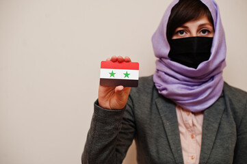 Portrait of young muslim woman wearing formal wear, protect face mask and hijab head scarf, hold...