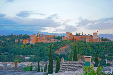 The Alhambra palace and fortress at dawn, Granada, Spain. City landscape with ancient Arabic fortress and Sierra Nevada mountains on horizon.