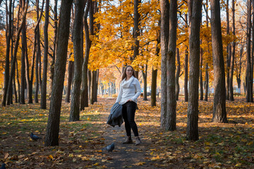 A young beautiful girl walks in the park on a sunny autumn day.