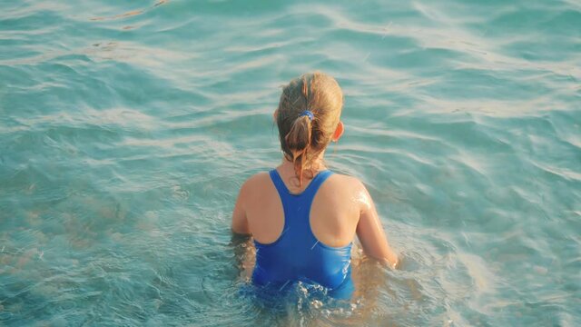 Cute child girl bathes in sea. Family vacation concept.
