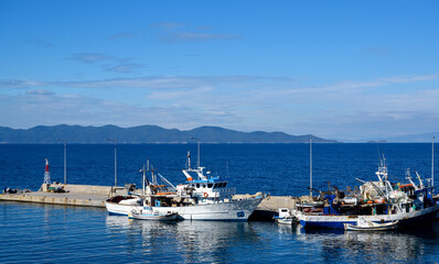 Fototapeta na wymiar Boats in the port of Nea Roda on blue sea water