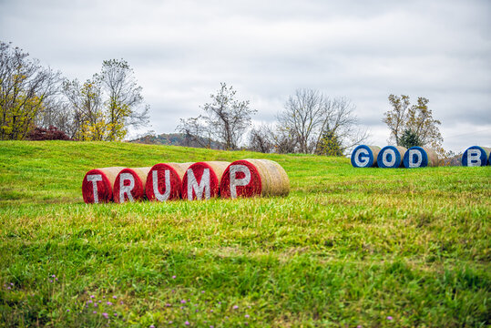 Washington, USA - October 27, 2020: God Bless America and Donald Trump slogan text during US presidential election painted on hay bales in Virginia rural countryside farm field