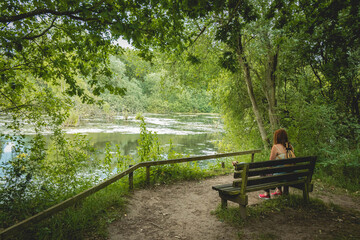 Fototapeta na wymiar woman in contemplative mood on park bench by pond