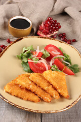 Georgian cuisine. Fried suluguni with tomato, onion and coriander salad in a beige plate on a wooden background. The Narsharab sauce. Pomegranate. Rustic. Background image
