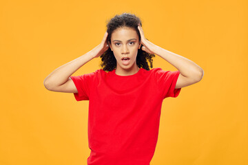 Woman with black curly hair holds her hand on her head red t-shirt 